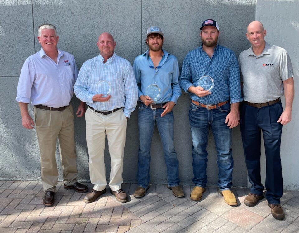 Group of five men standing against a building. The three in the middle are holding Life Saving awards.